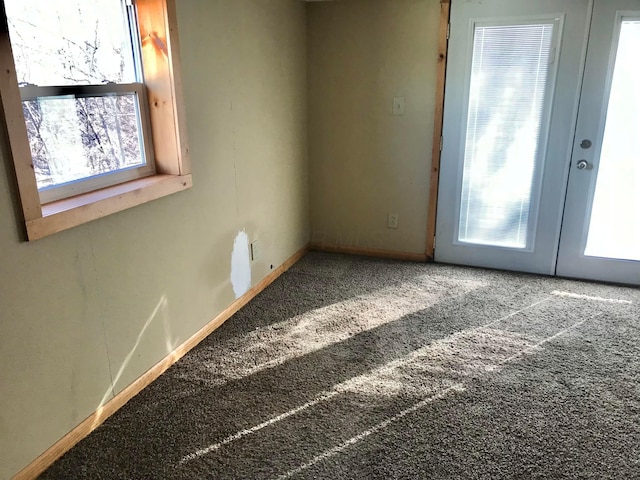 carpeted empty room featuring french doors and baseboards