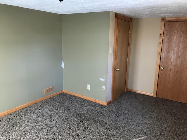 unfurnished room with carpet flooring, baseboards, visible vents, and a textured ceiling