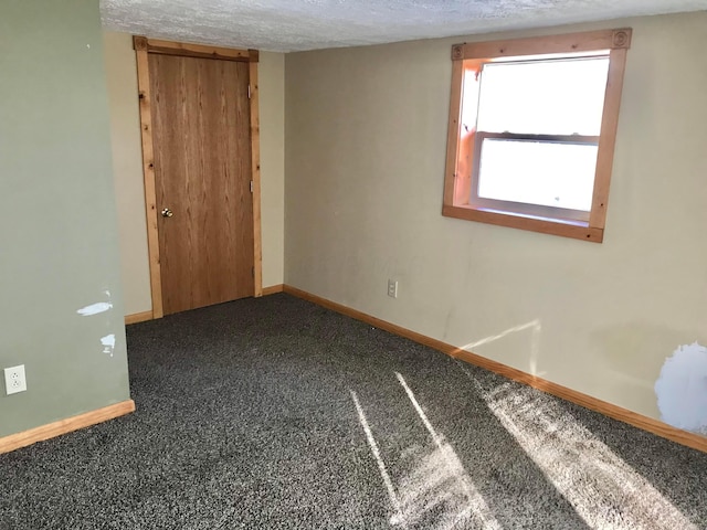 carpeted spare room featuring baseboards and a textured ceiling