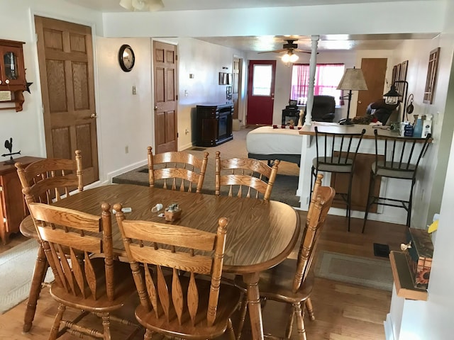 dining room featuring baseboards, light wood-type flooring, and a ceiling fan