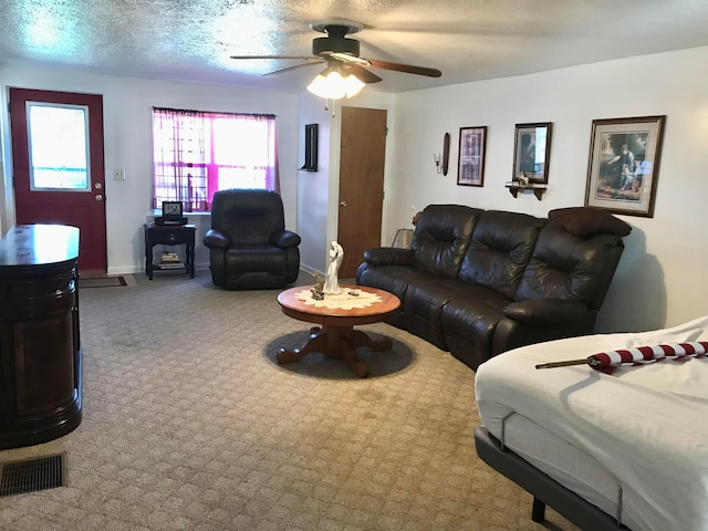 living area with a ceiling fan, carpet, baseboards, and a textured ceiling