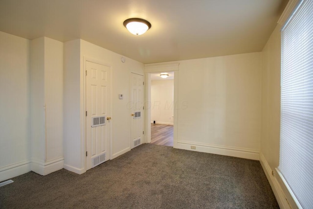 carpeted empty room featuring baseboards and visible vents