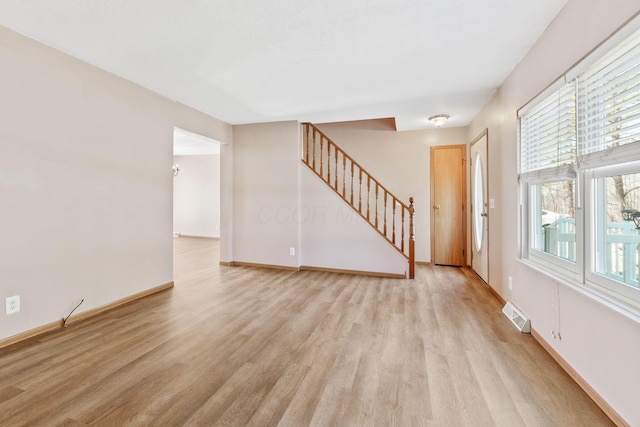 unfurnished living room with visible vents, stairway, light wood-type flooring, and baseboards