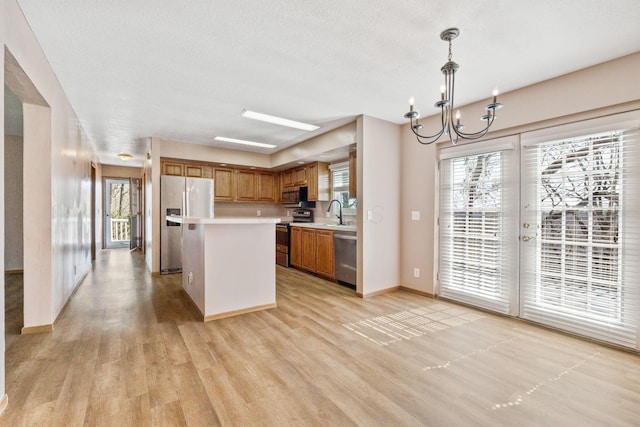 kitchen with a chandelier, light countertops, brown cabinets, appliances with stainless steel finishes, and light wood-style flooring