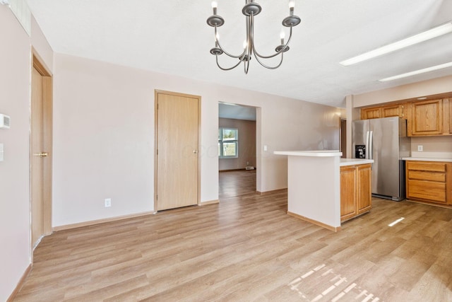 kitchen with light wood-style floors, light countertops, an inviting chandelier, and stainless steel fridge with ice dispenser