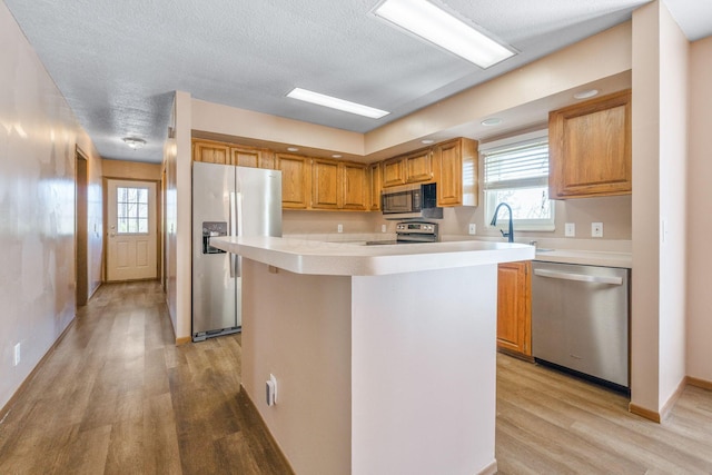 kitchen with a wealth of natural light, light wood-style flooring, stainless steel appliances, and light countertops