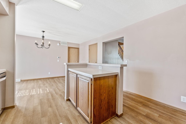 kitchen with light wood-type flooring, a notable chandelier, visible vents, and light countertops