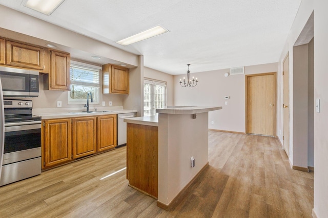 kitchen with light wood finished floors, visible vents, light countertops, appliances with stainless steel finishes, and a sink