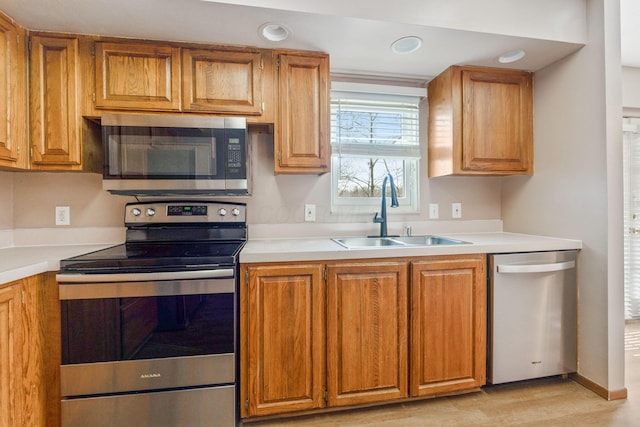 kitchen with a sink, brown cabinets, appliances with stainless steel finishes, and light countertops