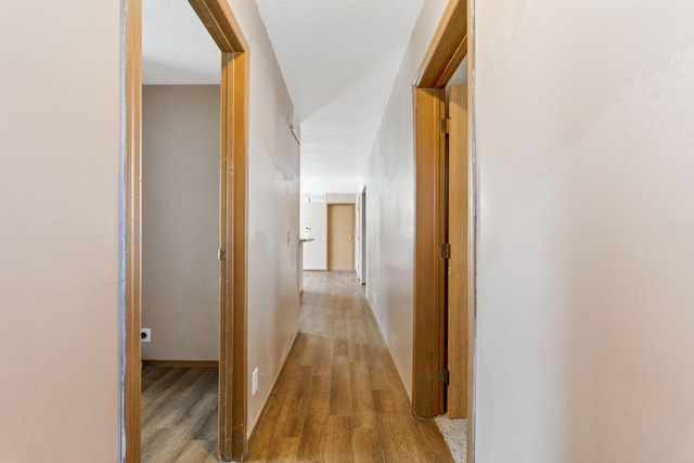 hall with baseboards and wood finished floors