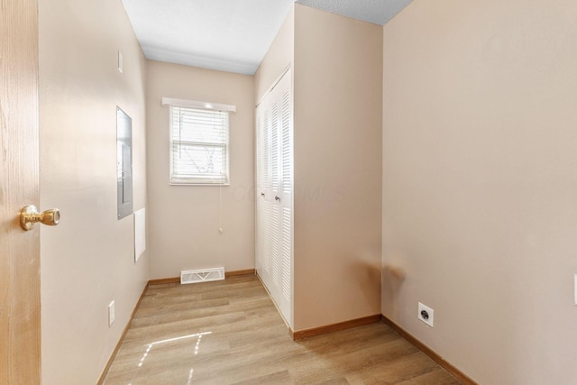 hallway featuring visible vents, baseboards, and light wood-style floors