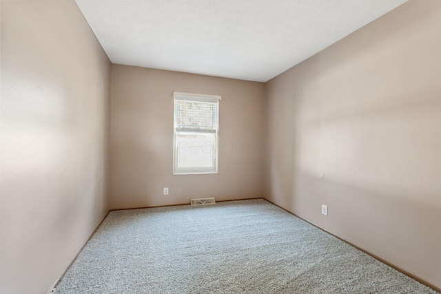 empty room with carpet flooring, visible vents, and a textured ceiling