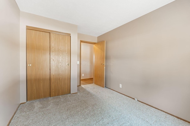 unfurnished bedroom with a closet, carpet floors, and baseboards