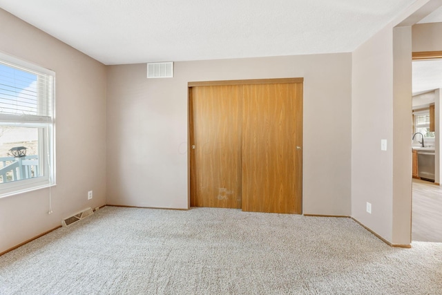 unfurnished bedroom featuring a closet, visible vents, baseboards, and carpet