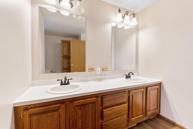 bathroom with double vanity, wood finished floors, baseboards, and a sink