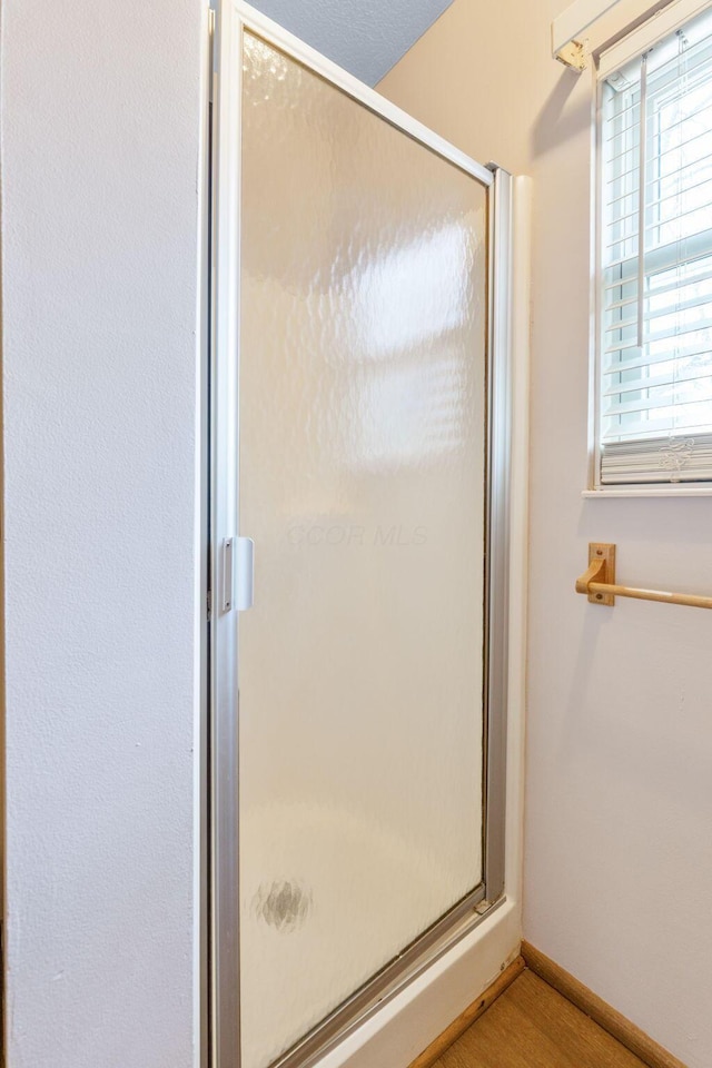 bathroom with a shower stall, wood finished floors, and baseboards