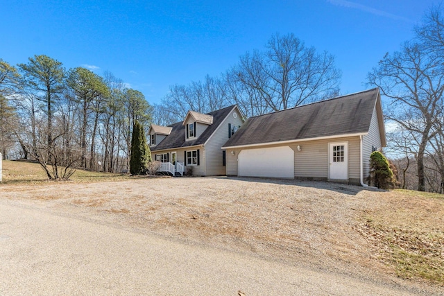 cape cod house featuring driveway and an attached garage