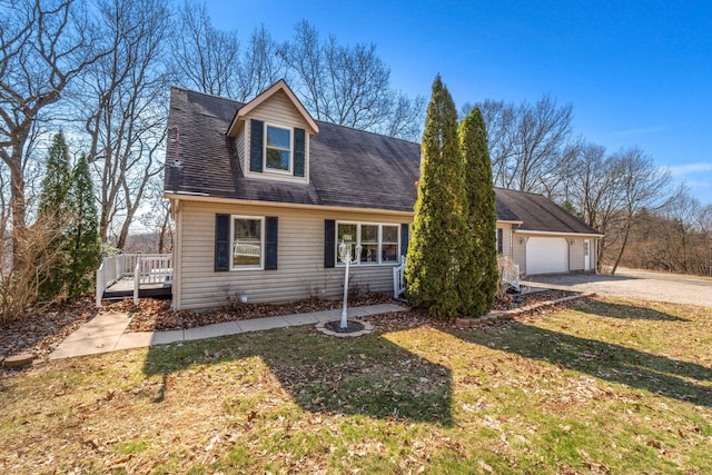 cape cod home with a deck, a front yard, an attached garage, and driveway