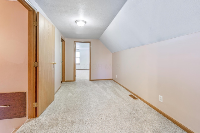 bonus room with baseboards, visible vents, lofted ceiling, a textured ceiling, and light carpet