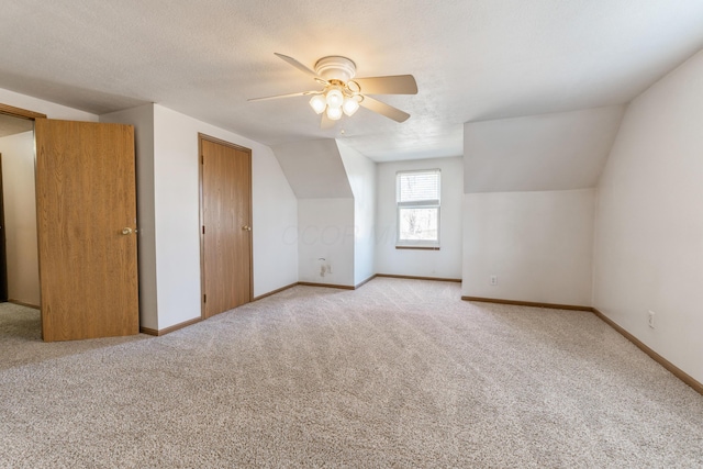 bonus room featuring light carpet, baseboards, a textured ceiling, and ceiling fan