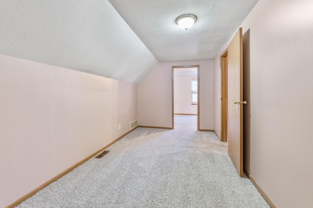 bonus room featuring visible vents, baseboards, a textured ceiling, and light carpet