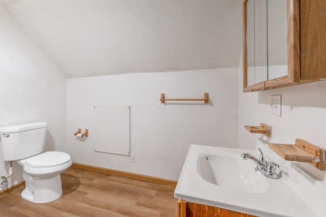 bathroom featuring vanity, wood finished floors, baseboards, lofted ceiling, and toilet