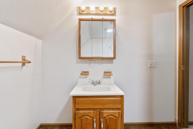 bathroom with vanity, vaulted ceiling, and a textured ceiling