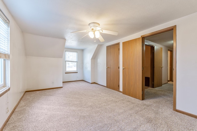 bonus room featuring lofted ceiling, carpet flooring, a ceiling fan, and baseboards