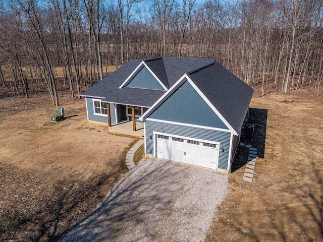 view of front facade with driveway, roof with shingles, covered porch, a garage, and central AC unit