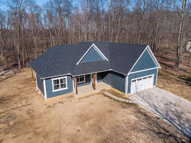 view of front of property featuring driveway, roof with shingles, covered porch, and an attached garage