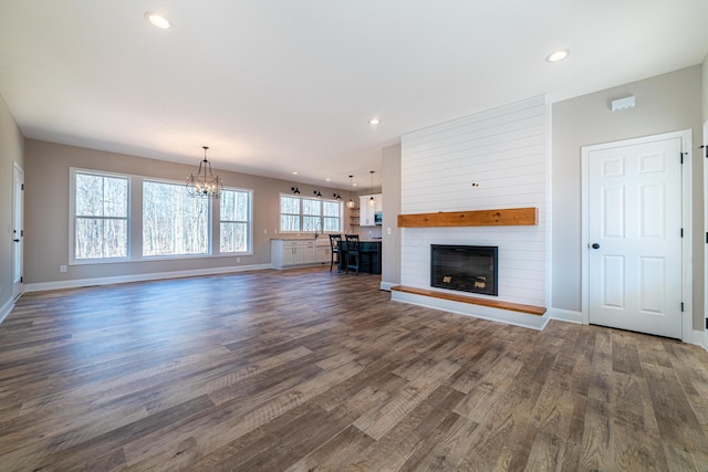 unfurnished living room featuring a fireplace, recessed lighting, dark wood-style floors, and baseboards