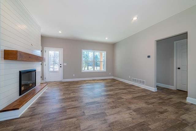 unfurnished living room with visible vents, baseboards, a fireplace, and dark wood-style flooring