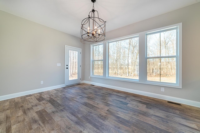 unfurnished dining area with dark wood finished floors, a notable chandelier, baseboards, and visible vents