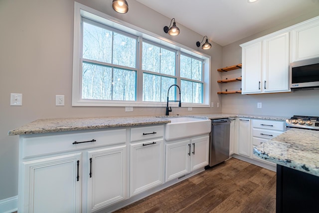 kitchen with light stone countertops, stainless steel appliances, a sink, dark wood-type flooring, and white cabinets