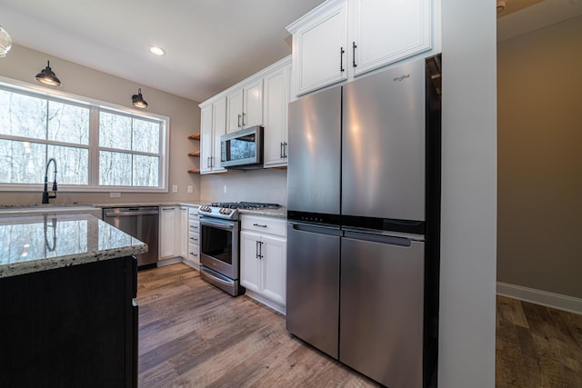 kitchen featuring light stone countertops, appliances with stainless steel finishes, light wood-style floors, white cabinets, and a sink