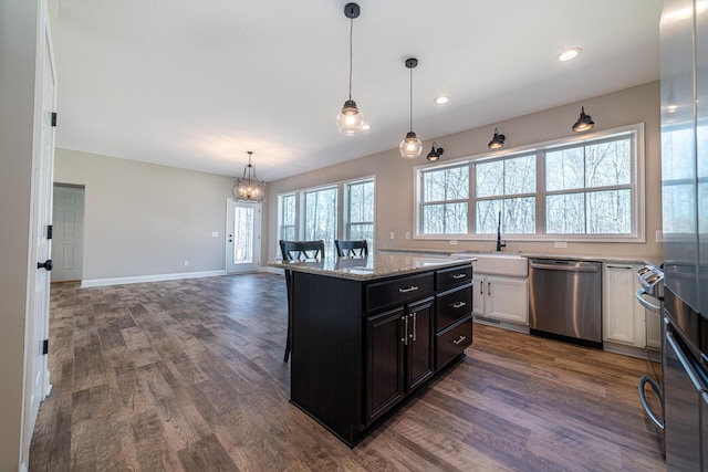 kitchen featuring dark wood finished floors, stainless steel dishwasher, dark cabinetry, white cabinetry, and a sink