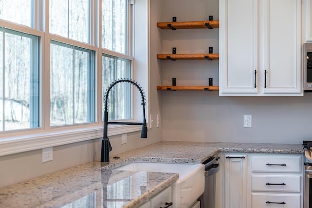 kitchen featuring a wealth of natural light, open shelves, white cabinets, and a sink