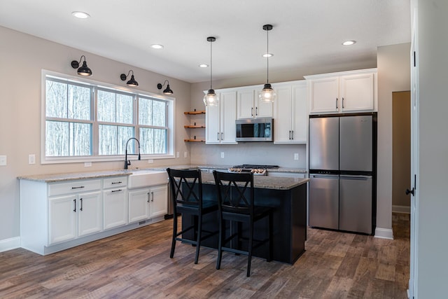 kitchen featuring a sink, stainless steel appliances, light stone countertops, and white cabinetry