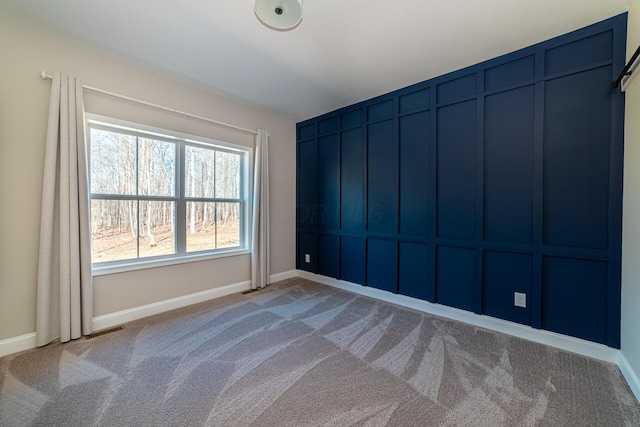 carpeted empty room with a decorative wall, baseboards, and visible vents