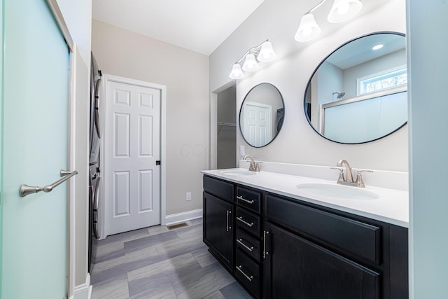 full bath featuring a sink, visible vents, baseboards, and double vanity