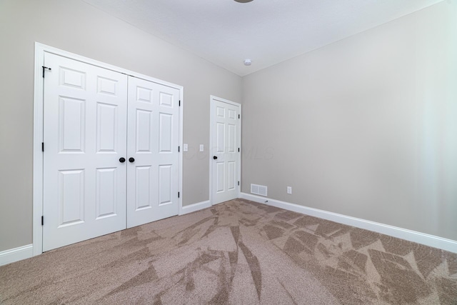 unfurnished bedroom with visible vents, baseboards, a closet, and carpet flooring