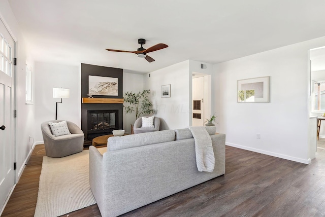 living room featuring visible vents, a fireplace, baseboards, and dark wood-style flooring