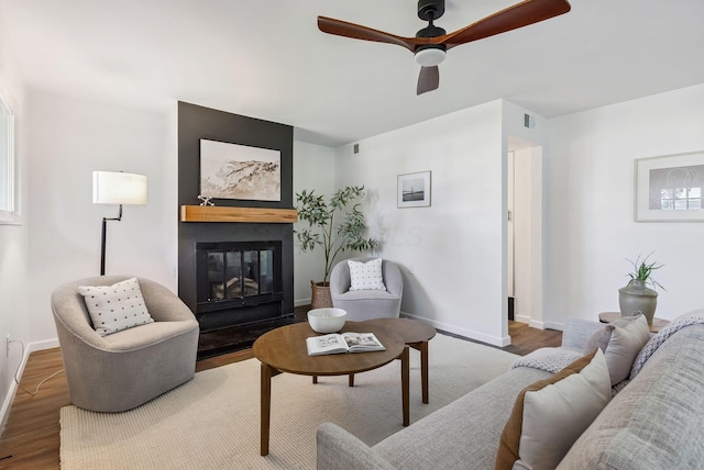 living room with visible vents, baseboards, a glass covered fireplace, and wood finished floors