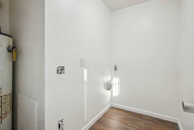 washroom featuring wood finished floors, baseboards, laundry area, water heater, and washer hookup