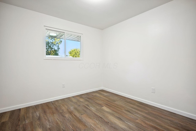 empty room with baseboards and dark wood-type flooring