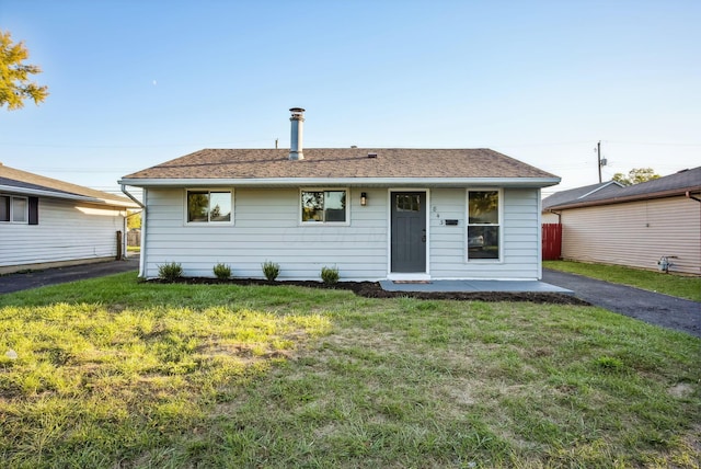 view of front of house featuring roof with shingles, a front yard, and fence