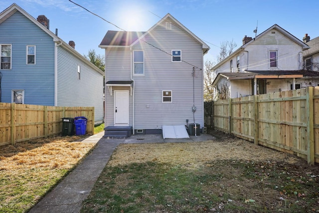 rear view of house with entry steps and a fenced backyard