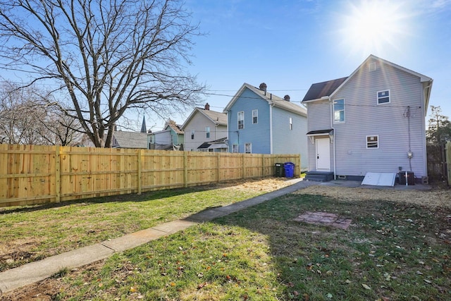 rear view of property with entry steps, a yard, and fence private yard