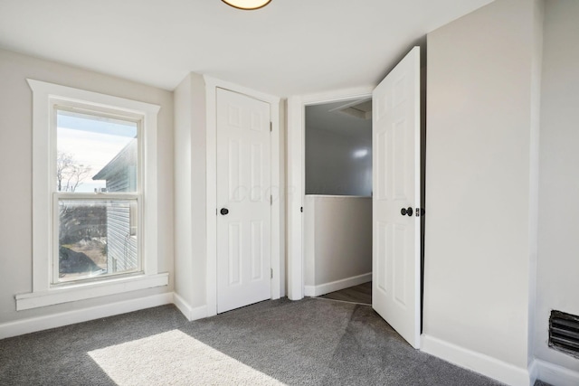 unfurnished bedroom featuring baseboards and dark carpet