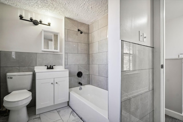 bathroom with toilet, marble finish floor, a textured ceiling, tile walls, and washtub / shower combination